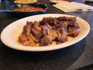 picture of beef plated with onions and kitchen in background