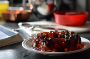 ring mold of purple jello with apples and grapes floating in it
