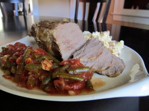 close up of pot roast on platter with green beans and potatoes