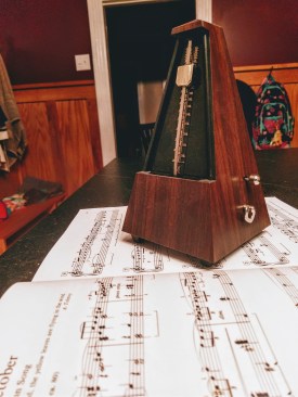 a pyramid metronome sitting on an open book of piano music